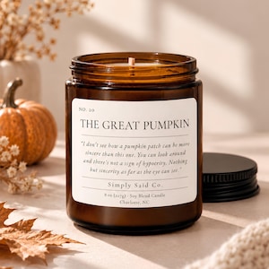 May include: An 8 oz (227g) soy blend candle in an amber glass jar with a black lid. The white label reads: NO. 20 THE GREAT PUMPKIN, followed by a quote about a pumpkin patch, Simply Said Co., and the weight and location details in Charlotte, NC.