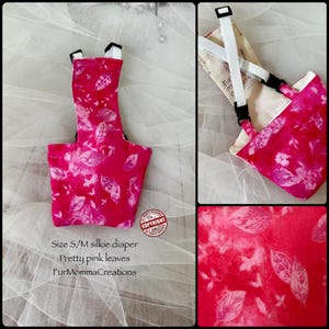 Puede incluir: Un pañal de seda rosa con un estampado de hojas. El pañal tiene correas ajustables y está diseñado para mascotas pequeñas y medianas. El texto en la imagen dice "Size S/M silkie diaper Pretty pink leaves FurMommaCreations."