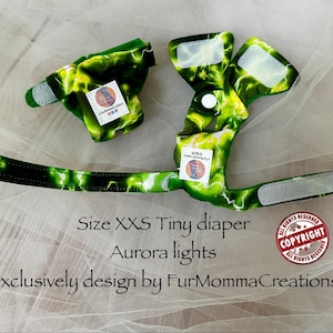 May include: A green and yellow lightning-patterned diaper with hook-and-loop fasteners and a white snap button. The text reads: Size XXS Tiny diaper, Aurora lights, Exclusively design by FurMommaCreations, and a red circular copyright stamp.