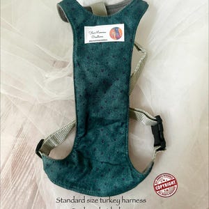 Pu&ograve; includere: Una pettorina per tacchino color verde ottanio scuro con un motivo a piccoli punti, cinghie in nylon beige e una fibbia in plastica nera. Un'etichetta rettangolare bianca &egrave; cucita sul davanti con il testo FurMommaCreations. Il testo Standard size turkey harness, Dark teal with dots, e FurMommaCreations &egrave; stampato sotto la pettorina.