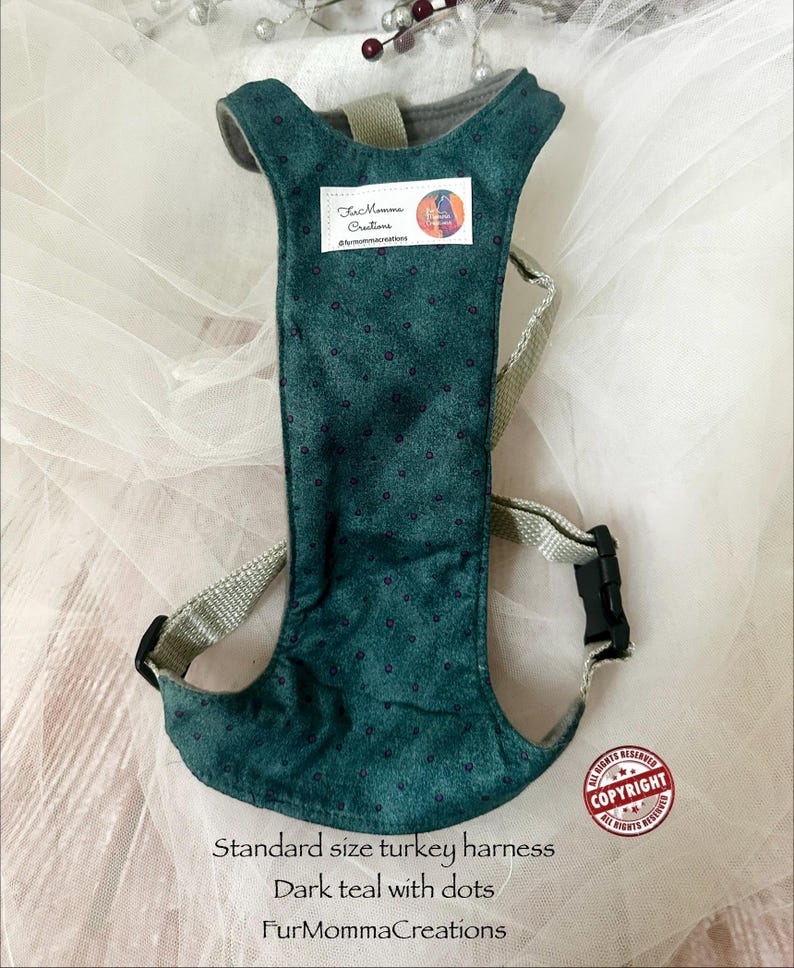 Pu&ograve; includere: Una pettorina per tacchino color verde ottanio scuro con un motivo a piccoli punti, cinghie in nylon beige e una fibbia in plastica nera. Un'etichetta rettangolare bianca &egrave; cucita sul davanti con il testo FurMommaCreations. Il testo Standard size turkey harness, Dark teal with dots, e FurMommaCreations &egrave; stampato sotto la pettorina.