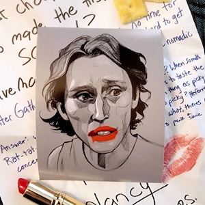 May include: A black and white drawing of a person with red lipstick. The drawing is on a white card with handwritten text that says "Nancy" and "P.S.".