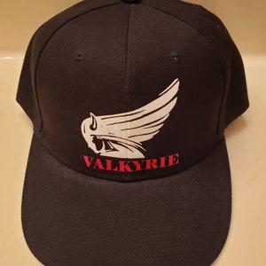 May include: Black baseball cap with a white winged design and the word "VALKYRIE" in red lettering.