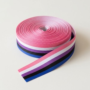 May include: A spool of grosgrain ribbon featuring a horizontal striped pattern in shades of pink, white, purple, black, and blue. The ribbon is tightly wound into a circular coil with one end extending outward to display the full colour sequence.