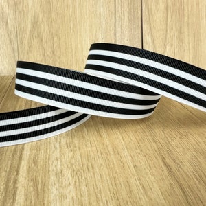 May include: Three rolls of black and white striped ribbon. The ribbon is a thick, woven fabric with a satin finish.