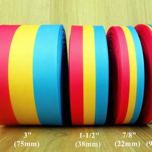 Op de afbeelding: Vier rollen gestreept lint in rood, geel en blauw. De lintbreedtes zijn 3 inch (75 mm), 1-1/2 inch (38 mm), 7/8 inch (22 mm) en 3/8 inch (9 mm).