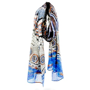 May include: A colourful patterned scarf with blue, white, orange, and black colours. The scarf has a geometric design with circles and dots.