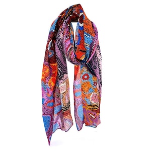 May include: A colourful scarf with a patterned design featuring dots, swirls, and abstract shapes in shades of red, orange, blue, pink, and black.