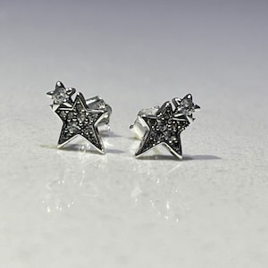 May include: A pair of silver star stud earrings with small clear cubic zirconia stones.