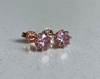May include: A pair of rose gold stud earrings with pink cubic zirconia stones.