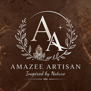May include: A logo featuring the letters AA in a serif font, surrounded by a circular wreath of leaves and a small crystal cluster. Below the emblem, the text reads AMAZEE ARTISAN and Inspired by Nature, set against a dark brown marble background.