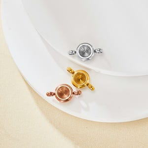 Op de afbeelding: Drie ronde metalen connector charms met een klein gaatje in het midden. De charms zijn zilver, goud en roségoud.
