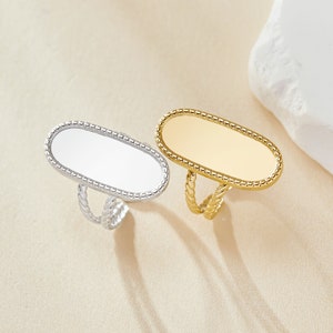 May include: Two oval-shaped rings with a beaded edge. One ring is silver and the other is gold.