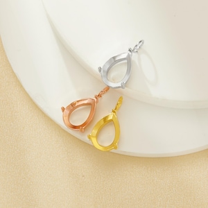 以下が含まれることがあります： 銀、ローズゴールド、ゴールドの、涙の形をしたペンダントセッティングが3つ。各セッティングには、チェーン用のループと宝石を保持するための小さな爪が付いています。ペンダントは白とベージュの表面に表示されています。