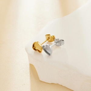 Könnte beinhalten: Ein Paar herzförmige Ohrringrohlinge, einer in Gold und einer in Silber, mit Stift und Schmetterlingsverschlüssen.