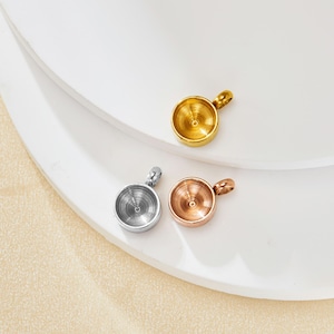 Puede incluir: Tres colgantes redondos de metal con un bucle en la parte superior. Los colgantes son de plata, oro y oro rosa.