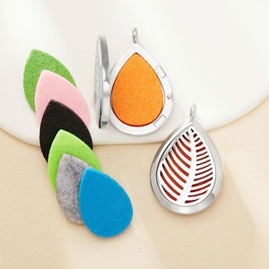 May include: Silver-tone teardrop-shaped essential oil diffuser pendants with leaf-shaped cutouts. Includes colorful felt pads in green, pink, black, light green, gray, and blue. The pendants have a hinged design for easy access to the felt pads.