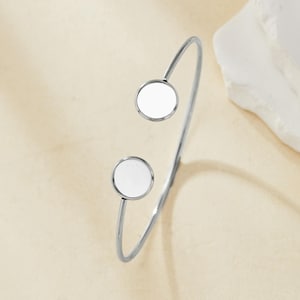 May include: A silver bangle bracelet with two white circular accents.