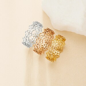 May include: Three dainty rings with a delicate floral design. The rings are made of metal and are available in silver, rose gold, and gold.