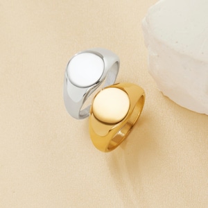May include: Two signet rings, one silver and one gold, with smooth, rounded tops.