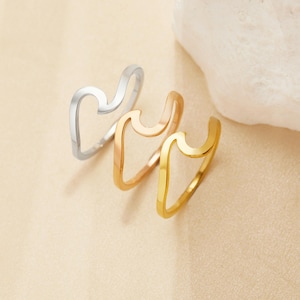 以下が含まれることがあります： シルバー、ローズゴールド、ゴールドの波形のリング3つ。リングは重ねられています。