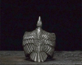 May include: A silver ring with a detailed design of a bird with its wings spread out.