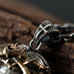 May include: A silver pendant necklace with a detailed cross design. The pendant features a textured, intricate design and is attached to a silver chain.