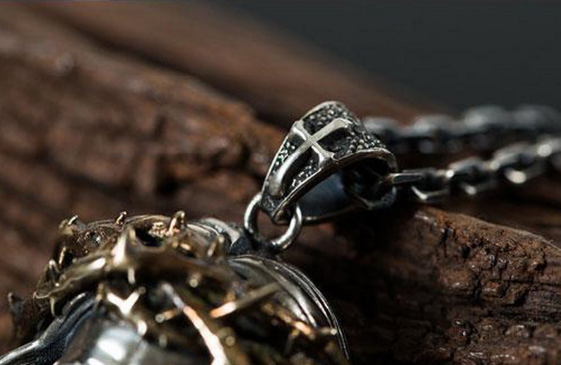 May include: A silver pendant necklace with a detailed cross design. The pendant features a textured, intricate design and is attached to a silver chain.
