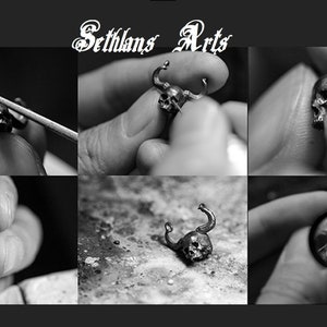 May include: A close-up of a silver skull pendant with horns being crafted by hand. The pendant is being held by a person's fingers. The image is divided into nine sections, with the top section showing the text "Sethlans Arts".