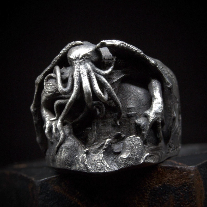 May include: A silver ring with a detailed sculpture of a Cthulhu-like creature with tentacles and wings.