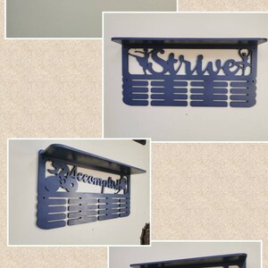 May include: Four medal display shelves with a ballerina silhouette. The shelves are painted in white and dark blue. The shelves are labeled "Hannah", "Strive", "Accomplish", and "Accomplish".