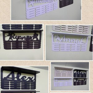 May include: A set of six personalized medal display racks. The racks are made of wood and have a shelf on top. The names "Braydon", "Alex", "Nicholas", "Ryan", "Anna", and "Alex" are displayed on the racks. The racks are painted in various colors, including white, beige, and black.