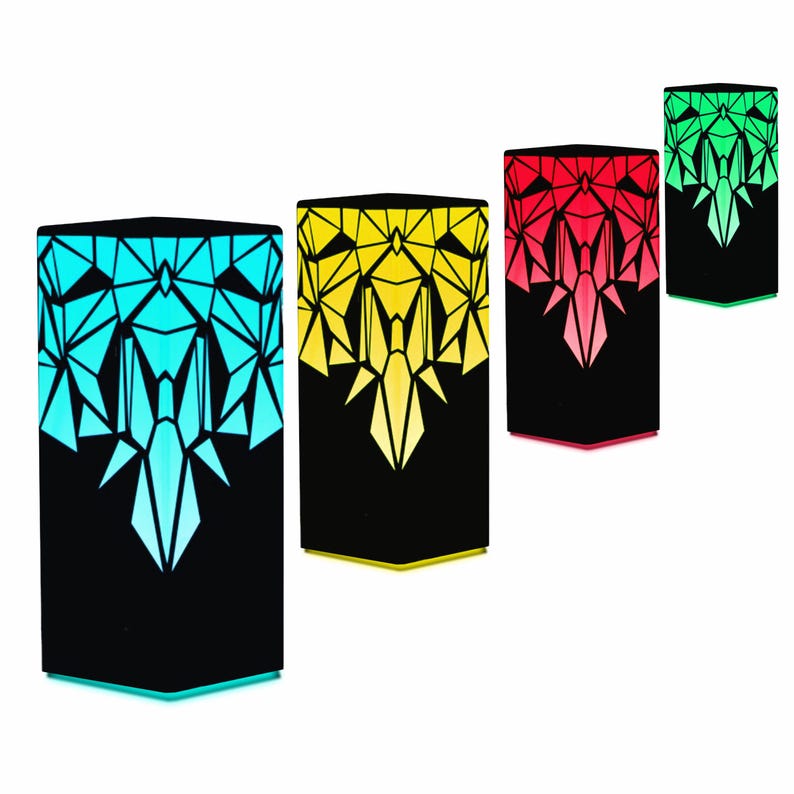 May include: Four geometric shaped lamps with a black base and a colorful geometric pattern. The lamps are lit in blue, yellow, red, and green.