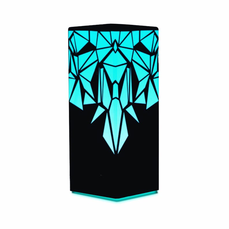 May include: A black geometric lamp with a teal light emanating from the geometric cutouts. The lamp is on a white background.