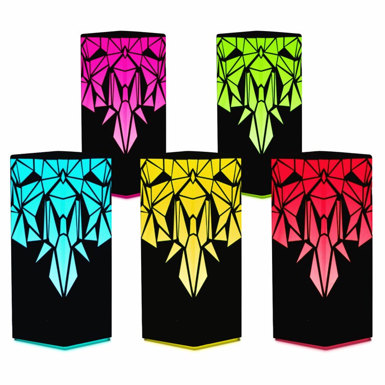 May include: Five geometric lamps with black bases and colorful geometric designs. The lamps are lit and glow in shades of pink, green, blue, yellow, and red.