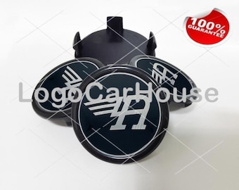 May include: Four black and silver car hubcaps with a stylized letter "A" and wings logo. The hubcaps are arranged in a circle with one hubcap on top of the others.
