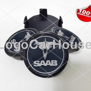 Könnte beinhalten: Vier schwarze und silberne Radkappen mit einem Kampfjet und dem Wort "SAAB" darauf gedruckt.