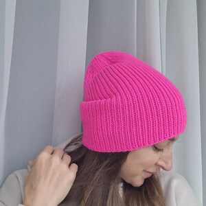 Op de afbeelding: Een felroze geribbelde gebreide beanie. De muts heeft een omgeslagen rand en een nauwsluitend ontwerp. De muts is gemaakt van een zacht, warm materiaal, ideaal voor de winter.