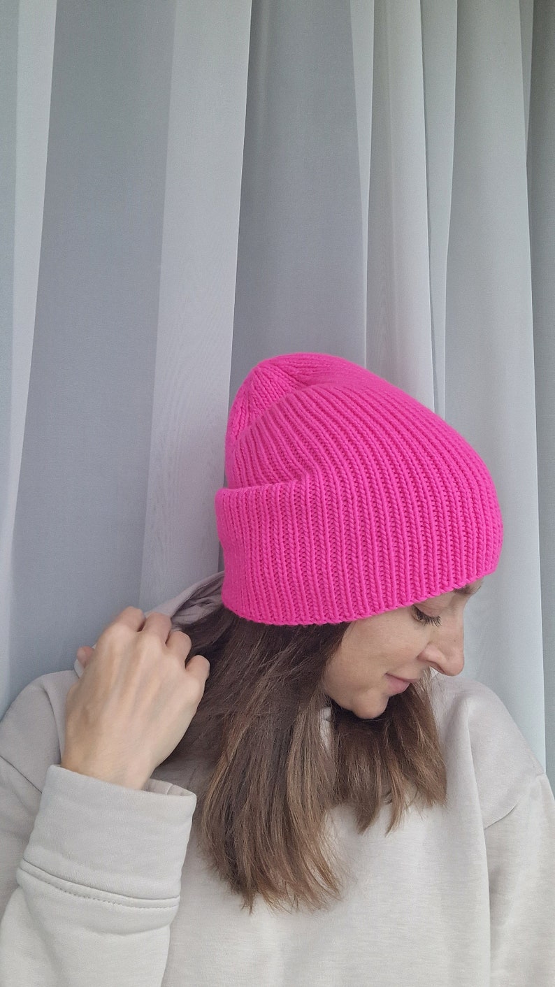 Op de afbeelding: Een felroze geribbelde gebreide beanie. De muts heeft een omgeslagen rand en een nauwsluitend ontwerp. De muts is gemaakt van een zacht, warm materiaal, ideaal voor de winter.
