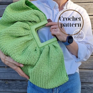 Op de afbeelding: Een grote, limoengroene gehaakte tas met een vierkante handgreep. De tas heeft een getextureerde, geweven uitstraling. De afbeelding bevat de tekst "Crochet pattern" en "PDF + Video". De tas wordt vastgehouden door een persoon die een wit overhemd en een blauwe spijkerbroek draagt.