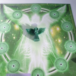 May include: Green and white angel wings with a green angel figurine in the centre. The background is a green and gold design with a circle of smaller green circles around the angel. The text "version 1" and "Copyright 2015 Avalon" are at the bottom of the image.