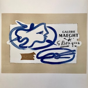 May include: A blue and white abstract art print with the text "Galerie Maeght" and a signature. The print is framed in a beige mat.