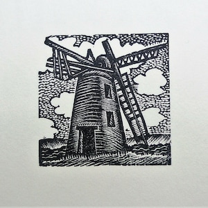 May include: A black and white linocut print of a windmill. The windmill has a tall, cylindrical body with a sloped roof and a ladder. The blades are angled, and the sky is filled with stylized clouds. The print is on a white background.