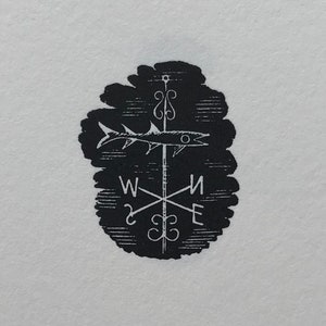 May include: Black and white illustration of a compass with a fish on top. The compass points north, south, east, and west.