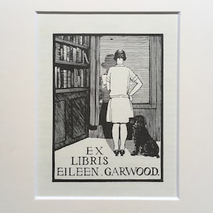 以下が含まれることがあります： 窓の外を眺める女性の白黒プリント。足元には犬がいます。左側には本棚があります。プリントには「EX LIBRIS EILEEN.GARWOOD」の文字が含まれています。