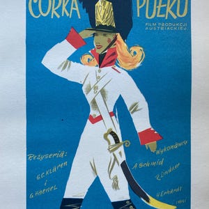 May include: A vintage movie poster for the film "Córka Pułku" (Daughter of the Regiment) in Polish. The poster features a woman in a white military uniform with a red sash and a black hat, holding a sword. The text on the poster is in Polish and includes the title of the film, the director's name, the actors' names, and the production company.