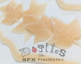 May include: Pale, leaf-shaped SFX prosthetics arranged on a white surface. The image features several of the leaf shapes, along with a curved, vein-like piece. The text "Dotties Do SFX Prosthetics" is visible.