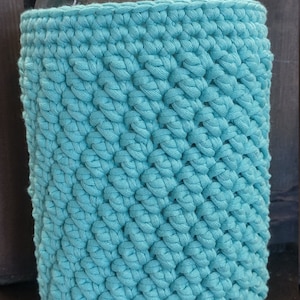 May include: A turquoise crocheted jar cosy for a glass jar with a white lid.