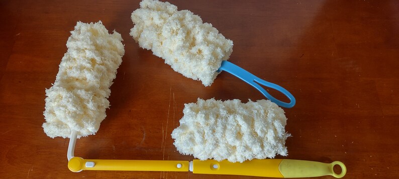 May include: Three cleaning brushes with fluffy, cream-colored microfiber heads. Two have blue handles, and one has a yellow handle. The brushes are designed for cleaning and dusting.