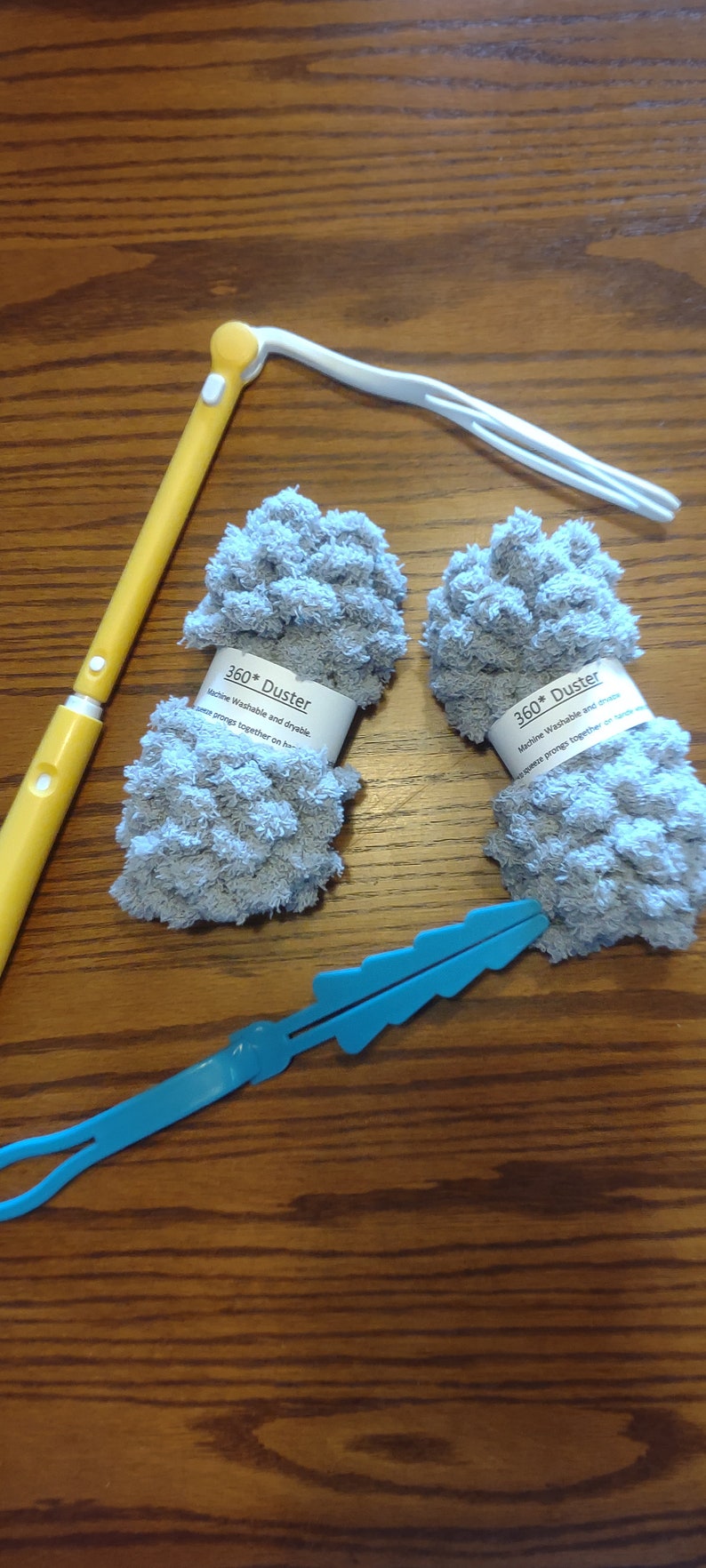May include: Two gray microfiber dusters with the text "360* Duster Machine Washable and dryable. Squeeze prongs together on handle."  A yellow and white duster handle and a blue cleaning tool are also pictured.